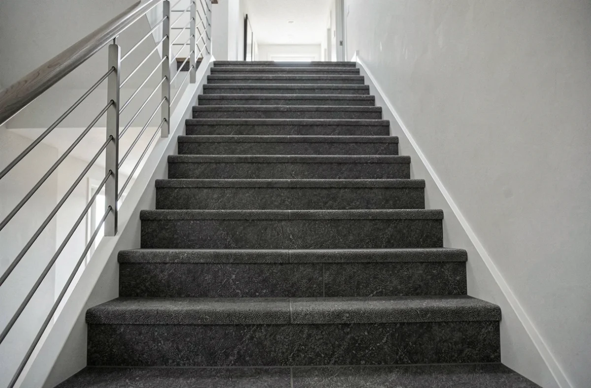 Escalier moderne en moquette gris anthracite avec marches recouvertes de dalles moquette sur toute la largeur dans un intérieur scandinave épuré